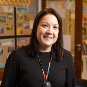 Smiling lady in a school wearing a lanyard.