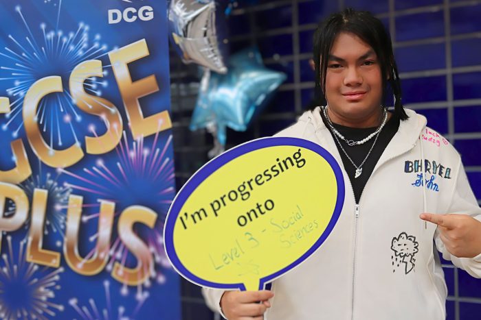 Young man holding a green board in the shape of a speech bubble.