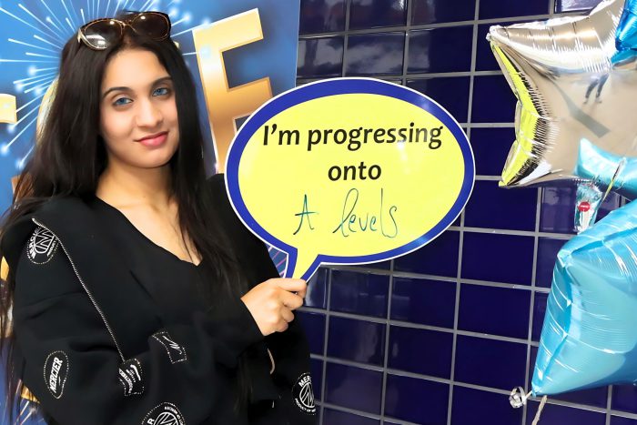 Young lady holding a board that reads 'I'm progressing onto A-levels'