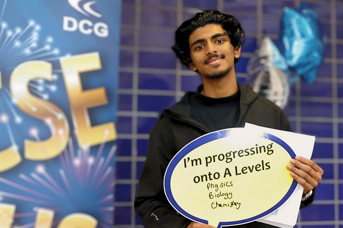 Young man holding a board that reads 'I'm progressing onto A-levels'