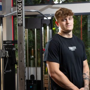 Young man stood by a weights machine.