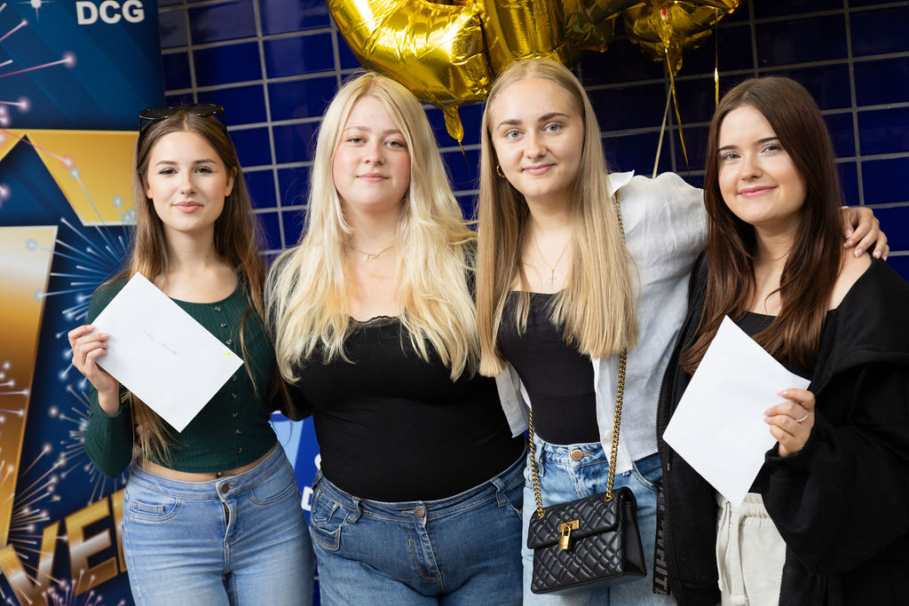 Four T Level Childcare students holding their result certificates.