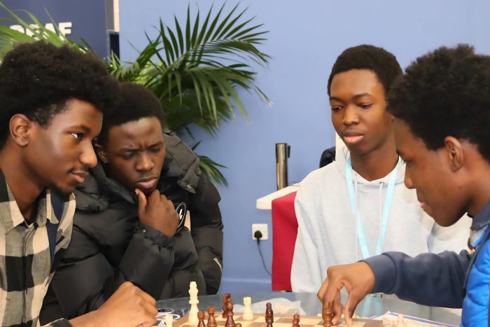 Four young men deep in thought, playing a game of chess.