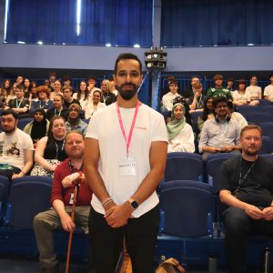 Young male stood in front of an audience of college students.