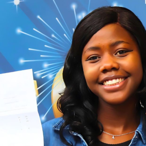 Young woman smiling, holding a piece of paper.