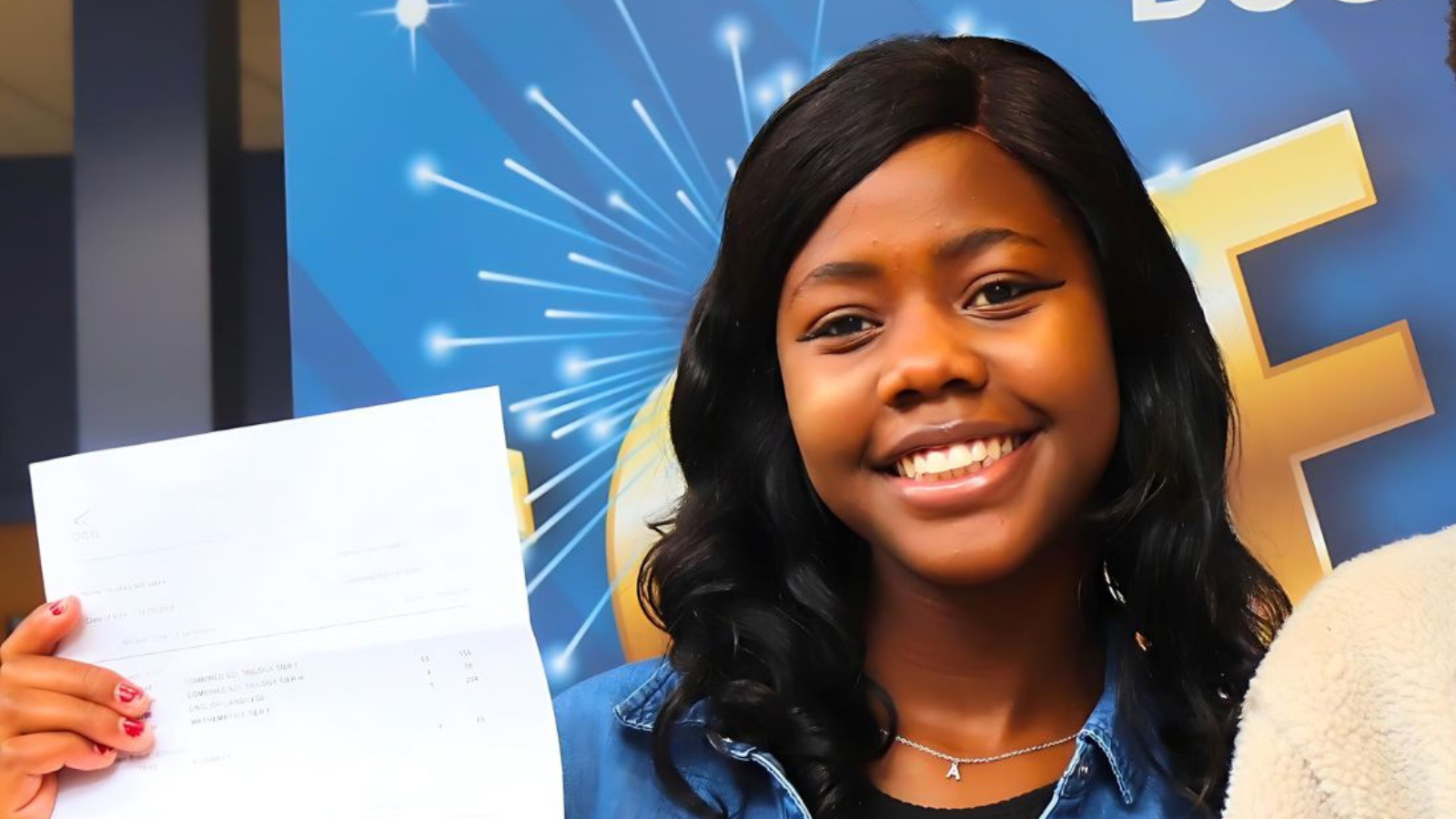 Young woman smiling, holding a piece of paper.