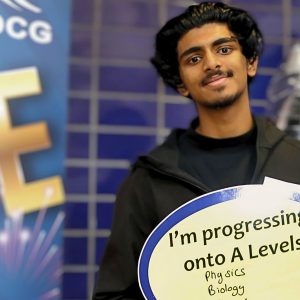 Smiling young man holding a sign with writing on it.