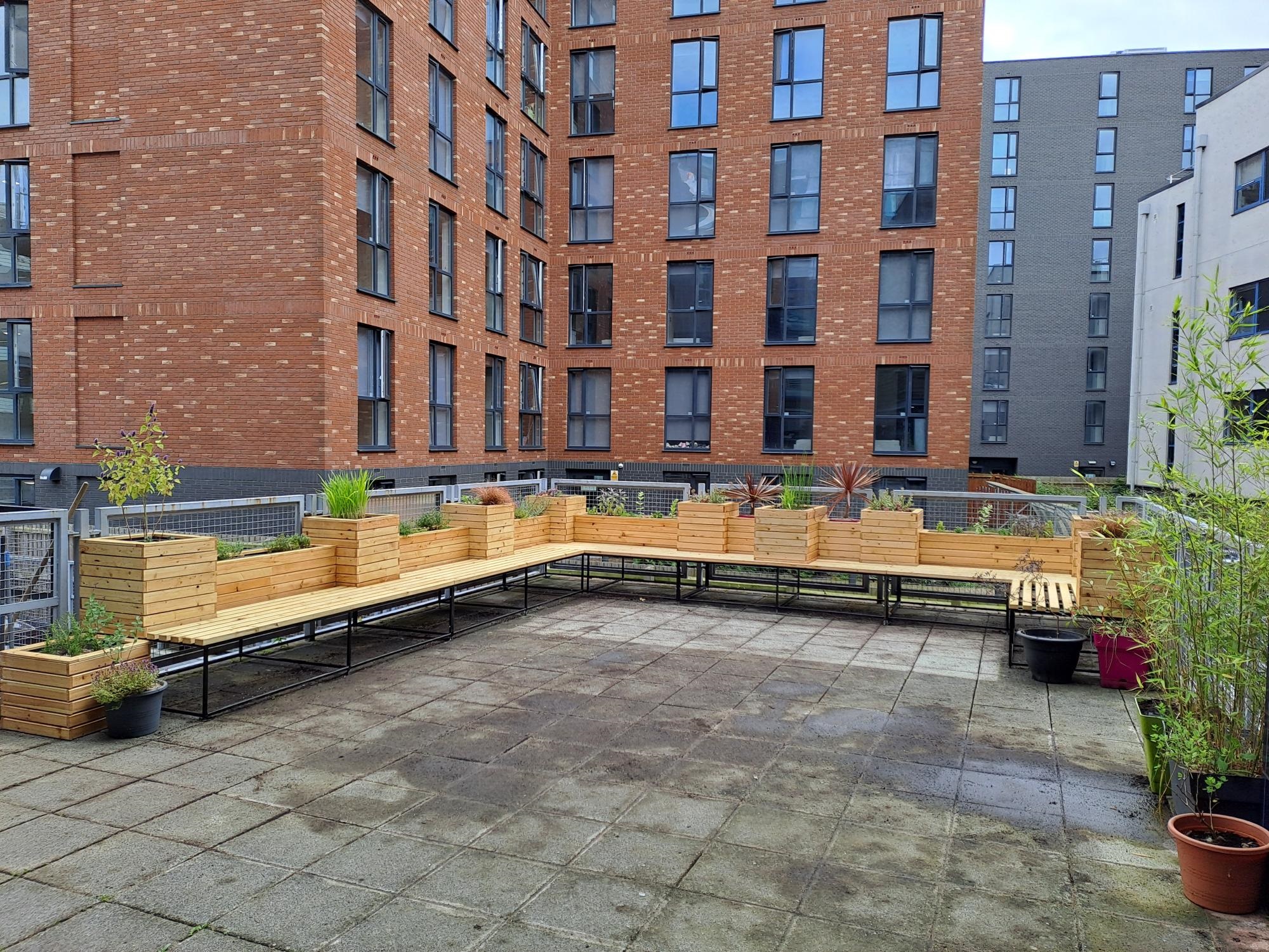 A paved garden with wooden benches and planters.