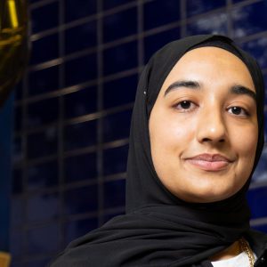 Young woman smiling stood against a blue background