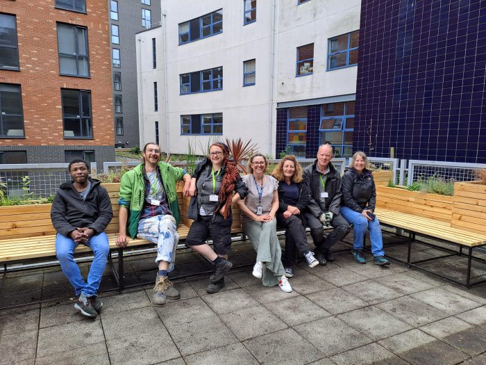 Adults sat upon wooden benches in a garden.