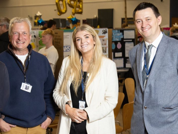 Derby College Group staff, two men and a woman stood together smiling.