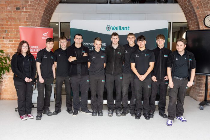 A large group of Vaillant and Derby College Group apprentices, young adults stood by a banner that reads 'Vaillant'