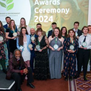 A group of people of mixed genders and ages holding awards at an awards ceremony.