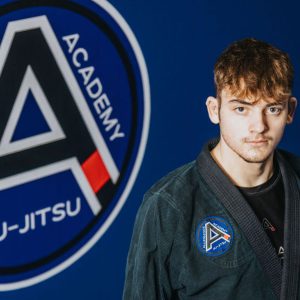 Young man with brown hair, wearing a jui-jitsu robe.