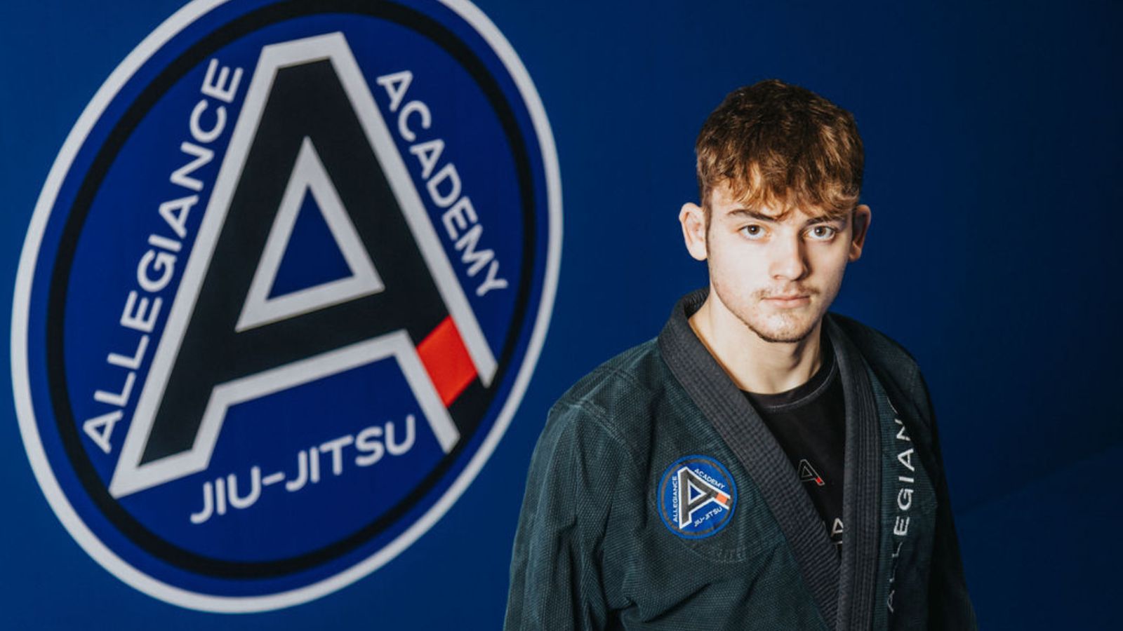 Young man with brown hair, wearing a jui-jitsu robe.