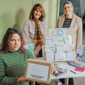 Three ladies holding pieces of a mental health toolkit.