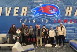 Young people stood in a group by a sign that reads 'River Hawks'.