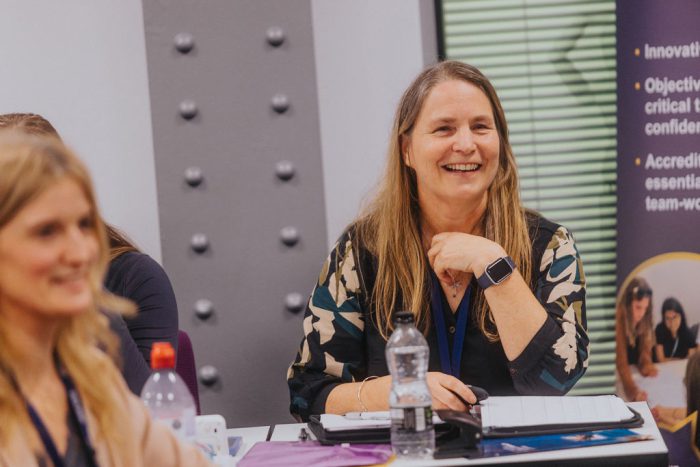 Female teacher smiling whilst watching a presentation.