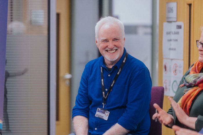 Smiling man wearing a blue shirt.